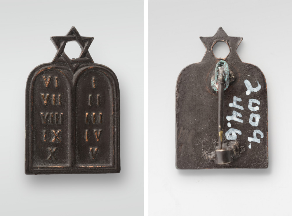 Two modern photographs of the front and back of a dark bronze-colored pin shaped like two stone tablets with a star of David on top