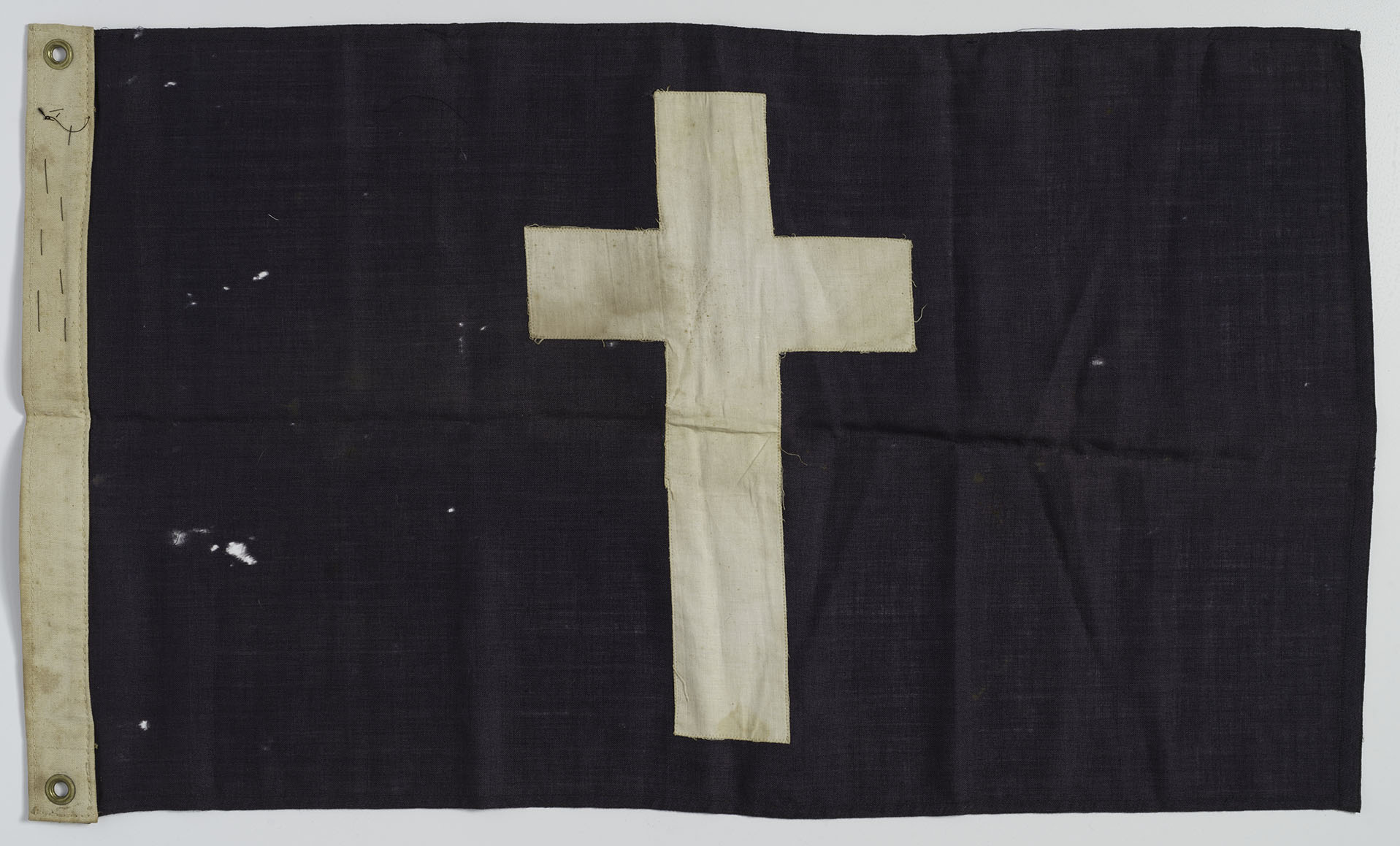 Modern photograph of a black rectangular flag with a white cross in the center