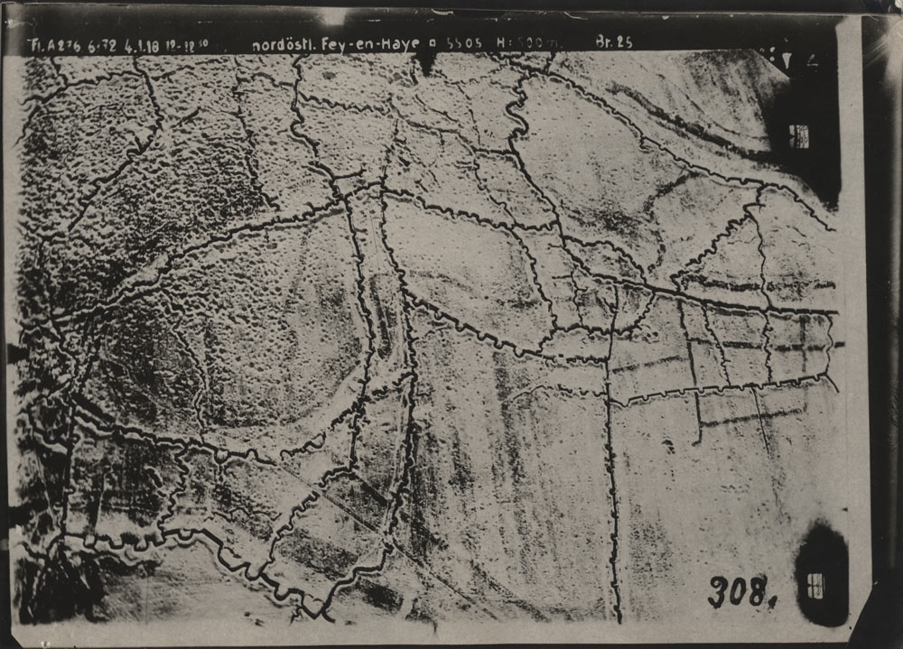 Black and white aerial photograph of a large flat area of fields and dirt criss-crossed with dark squiggly lines.