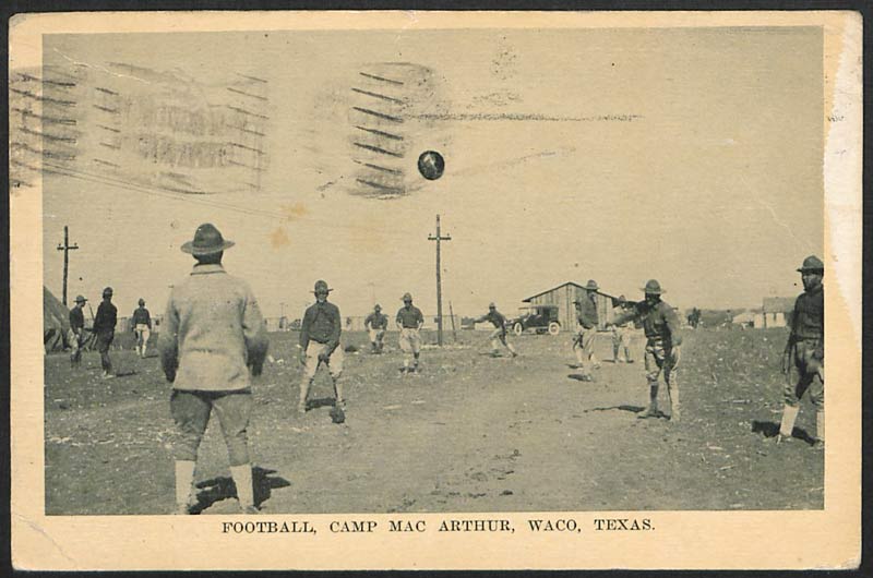 Photographie en noir et blanc d'un match de football nord-américain informel dans un terrain vide. Les joueurs portent tous des uniformes militaires et des chapeaux.