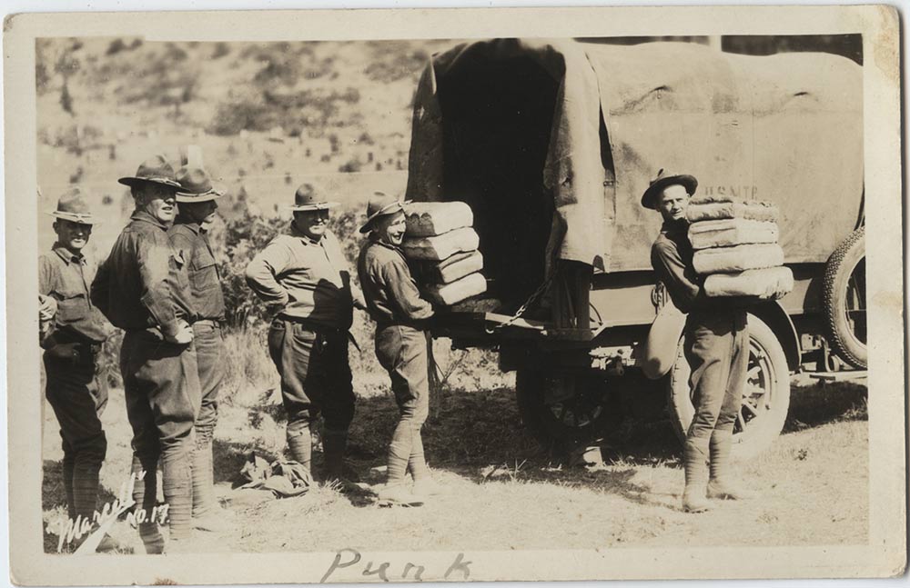 Photographie en noir et blanc de soldats américains de la Première Guerre mondiale en uniforme déchargeant des piles de pains à l'arrière d'un camion