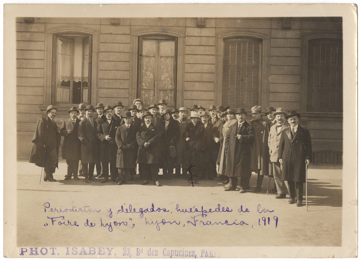 Photo sépia d'un groupe d'hommes et de femmes en pardessus et chapeaux regardant la caméra