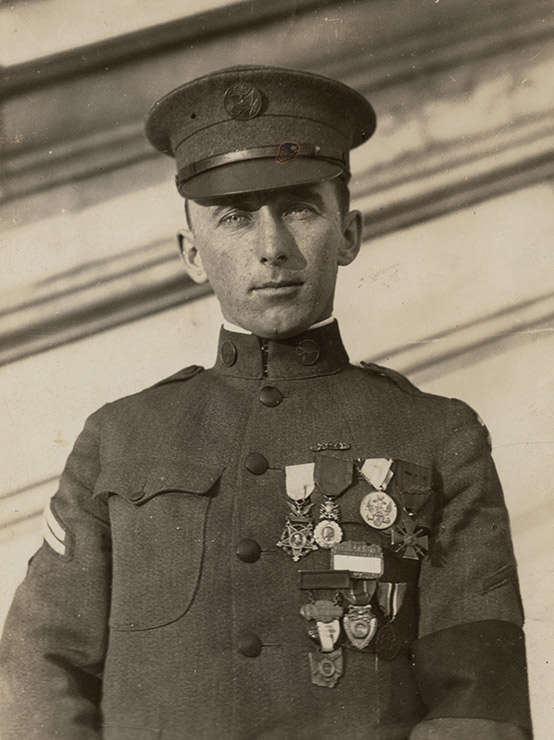 Sepia photograph portrait of a white man in WWI-era military uniform adorned with multiple medals
