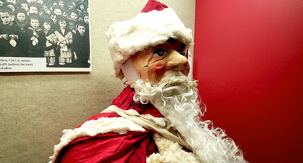 Photographie d'un costume de Père Noël sur mannequin comprenant un masque en papier peint.