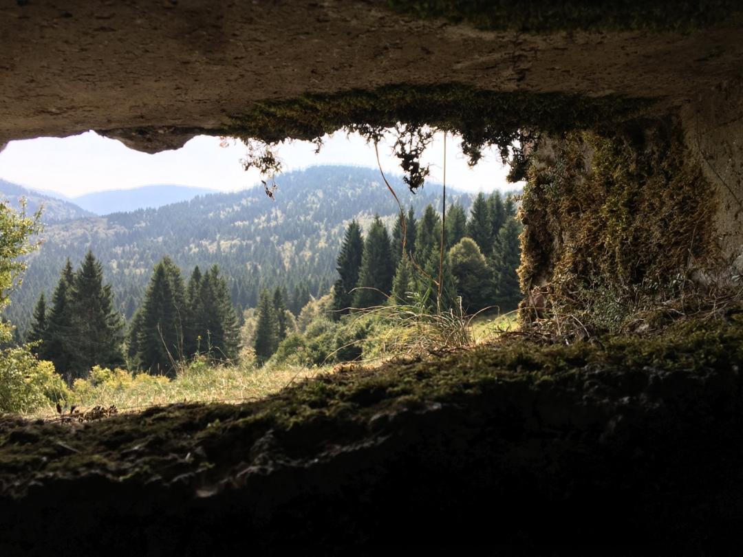 View from inside a cavelike structure looking out at a hilly landscape.
