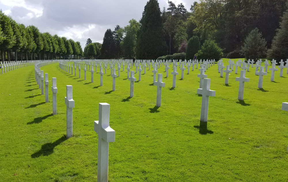 Rows of white crosses in a green lawn.