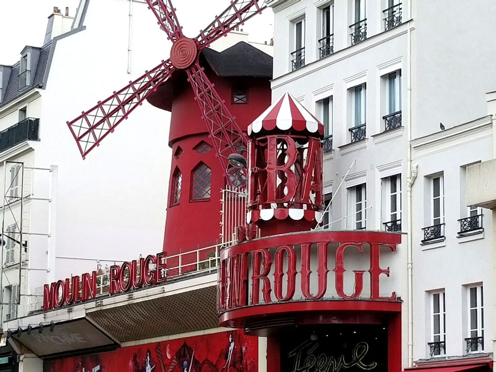 Photo of the front facade of Moulin Rouge - a red windmill.
