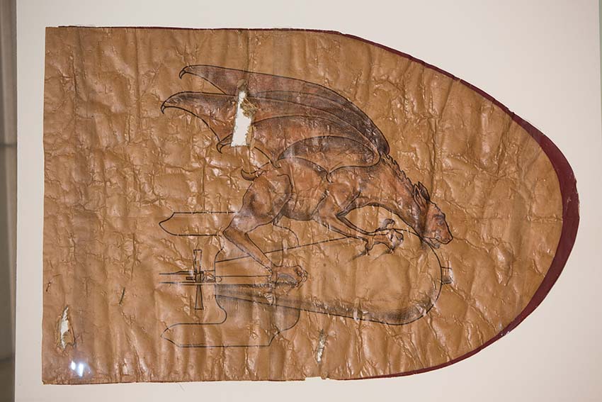 Photograph of a brown piece of fabric decorated with a hand-drawn chimera.