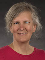 Headshot of a middle-aged white woman with tied-back grey hair wearing a magenta shirt.