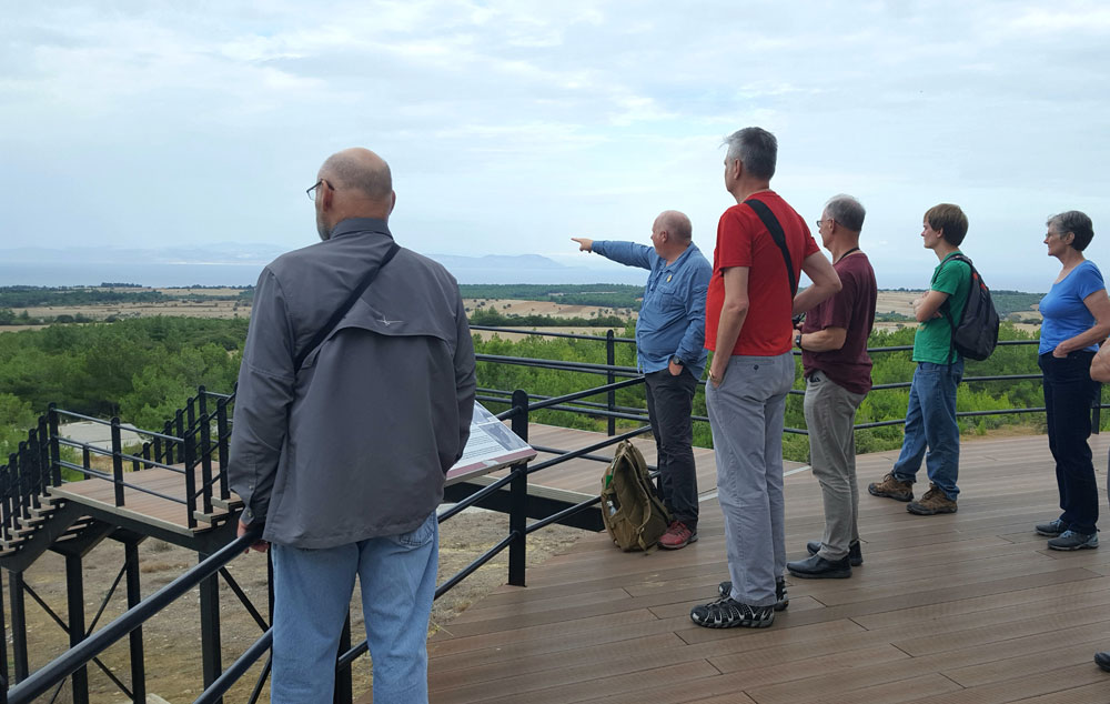 The tour group standing on a deck overlooking a green landscape.
