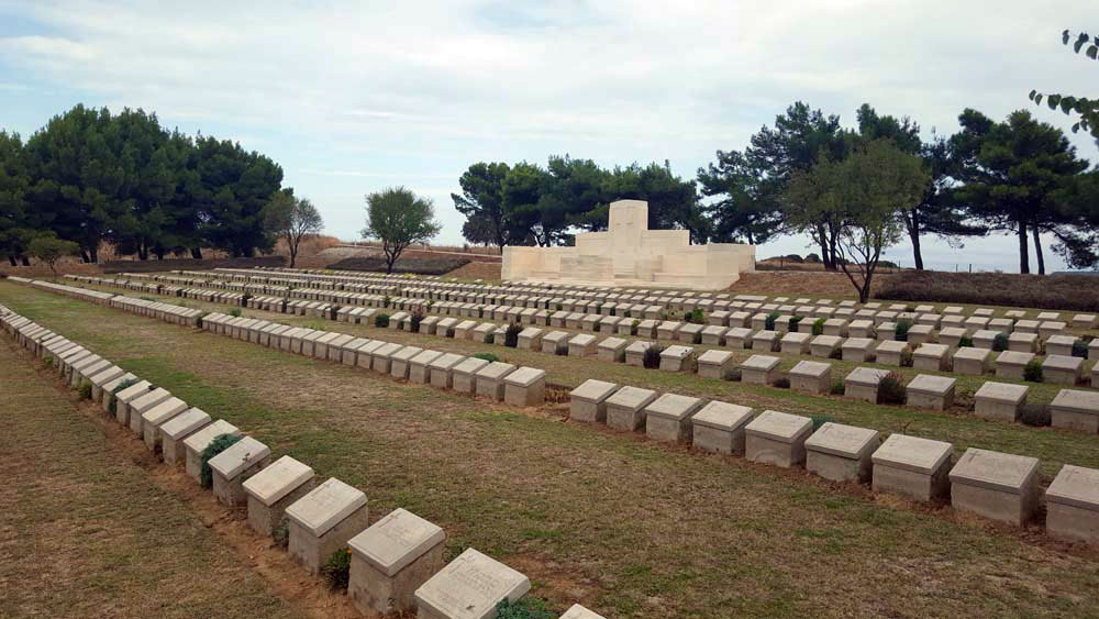 Rows of low rectangular grave markers in a lawn.