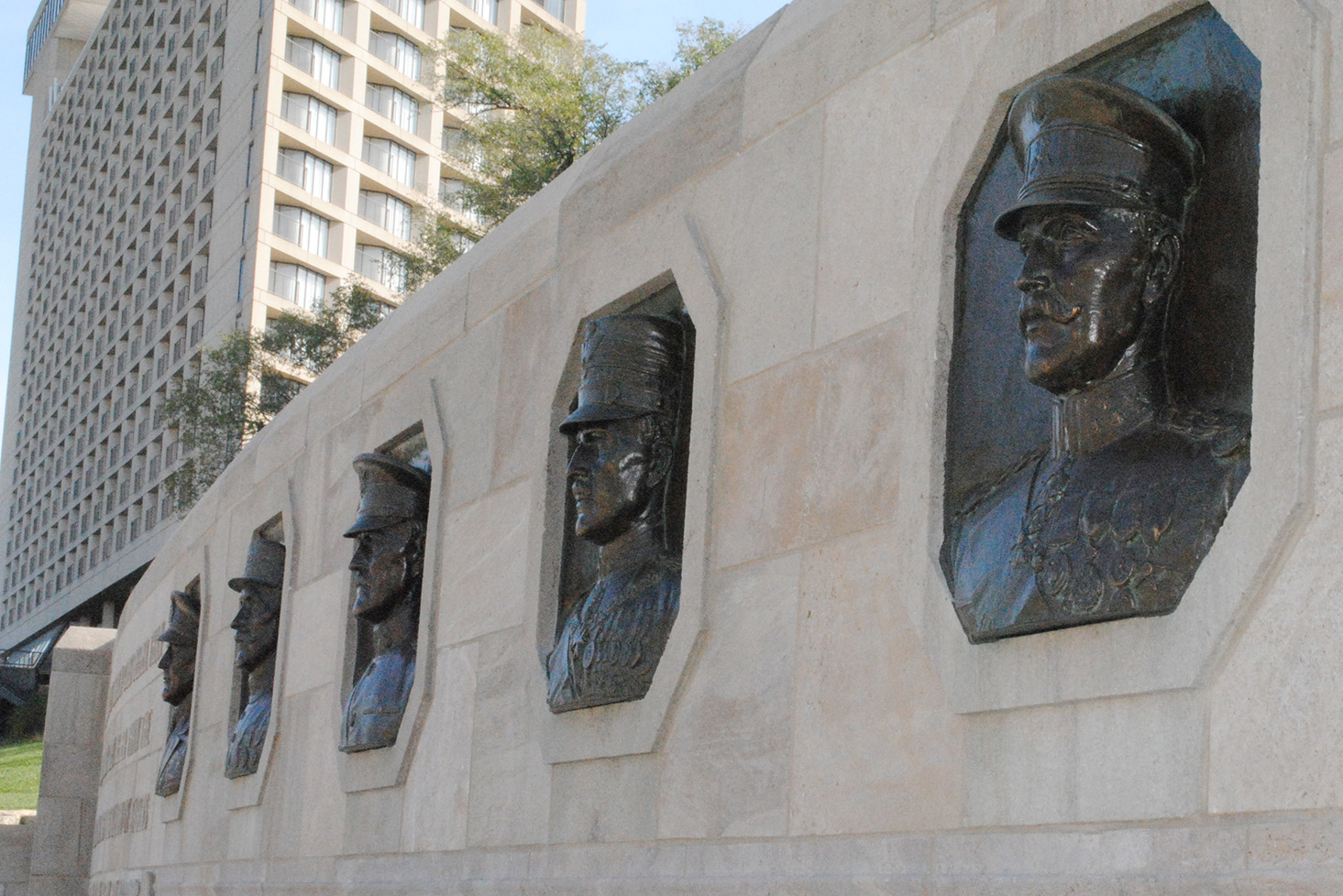 Angled view of a stone wall with five bronze bas-relief portraits of five generals.