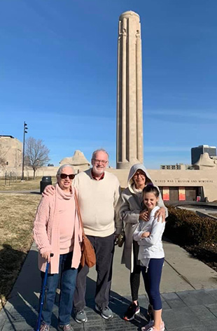 An older white woman, an older white man, a middle-aged white woman and a young white woman gathered in front of the Liberty Memorial Tower