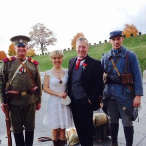 Color photograph of a white man and white woman dressed in wedding clothes on the grounds of the Museum and Memorial with two white men dressed in WWI reenactor clothes on either side of them.