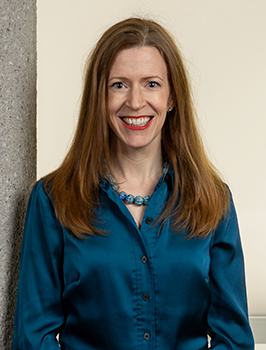 Modern photograph of a white woman with long brown hair wearing a deep teal button-down shirt