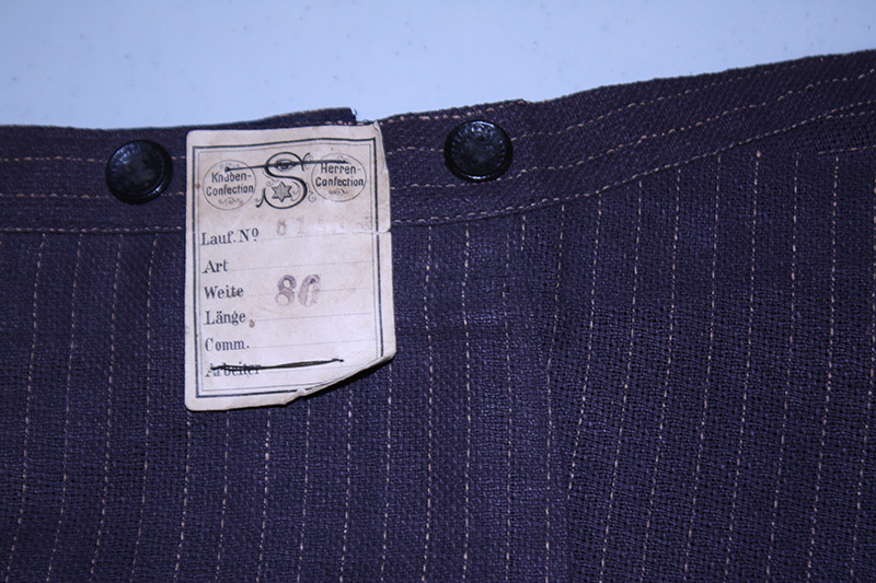 Modern photograph close-up of the waistband of blue pinstriped trousers with the label visible