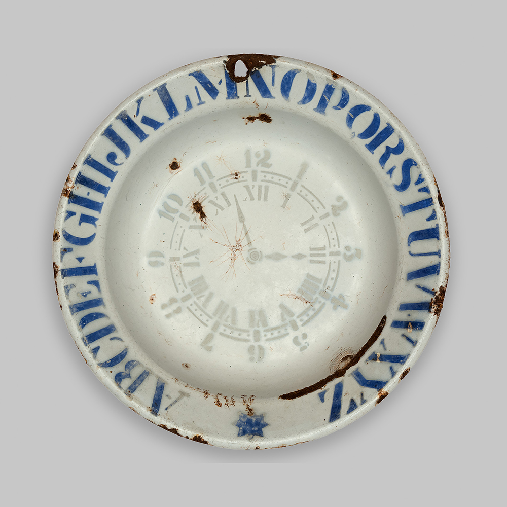 Modern photograph of a plate with Latinate letters painted around the edge.