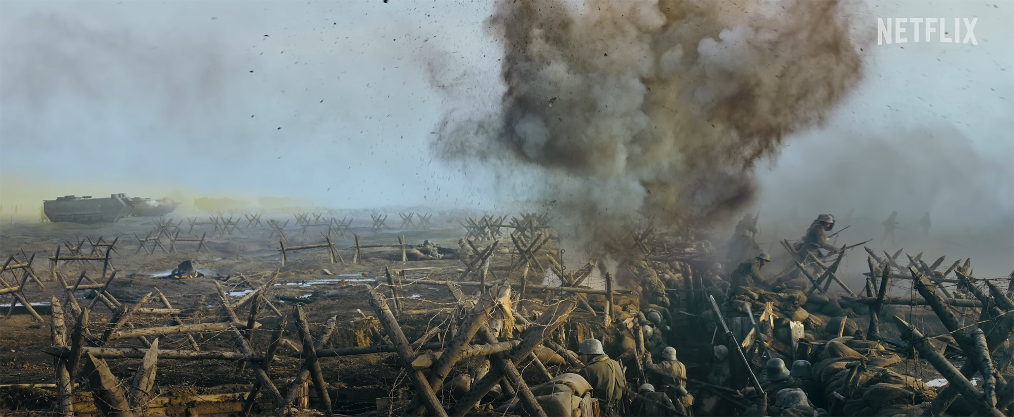 Film still of an explosion going off in a landscape of barbed wire and trench reinforcements