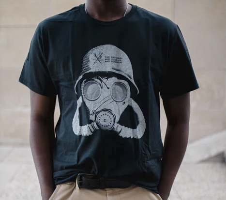 Photograph of a Black male model wearing a t-shirt printed with a gas mask and the Museum logo