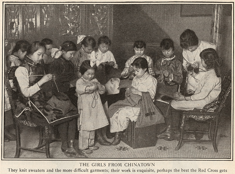 Black and white photograph of a group of seated Asian women and girls in the midst of knitting