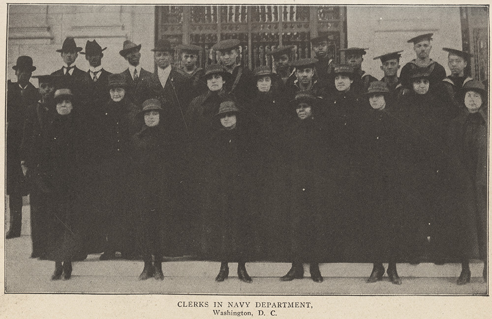 Black and white photograph of a group of Black women and men dressed in dark clothing and hats arranged on the outside steps of a building.