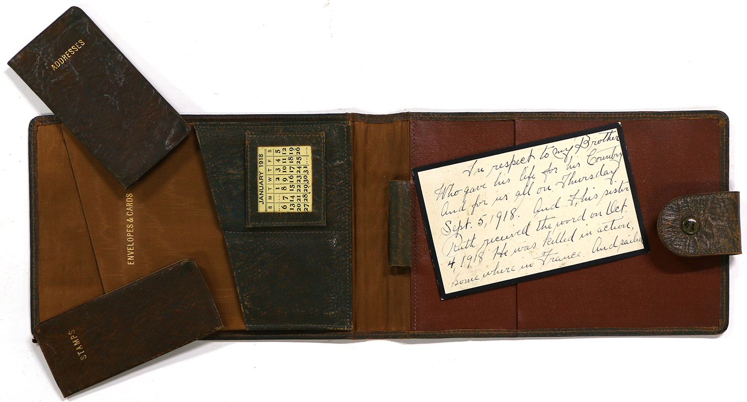 Modern photograph looking down at a flat lay of a leather portfolio with various writing accessories.