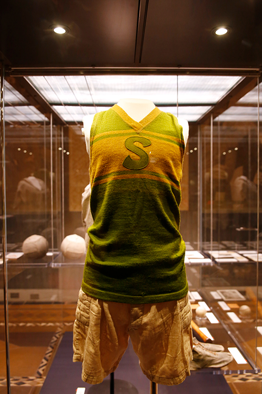 Photographie moderne d'un uniforme de basket-ball vert et jaune dans une vitrine en verre.