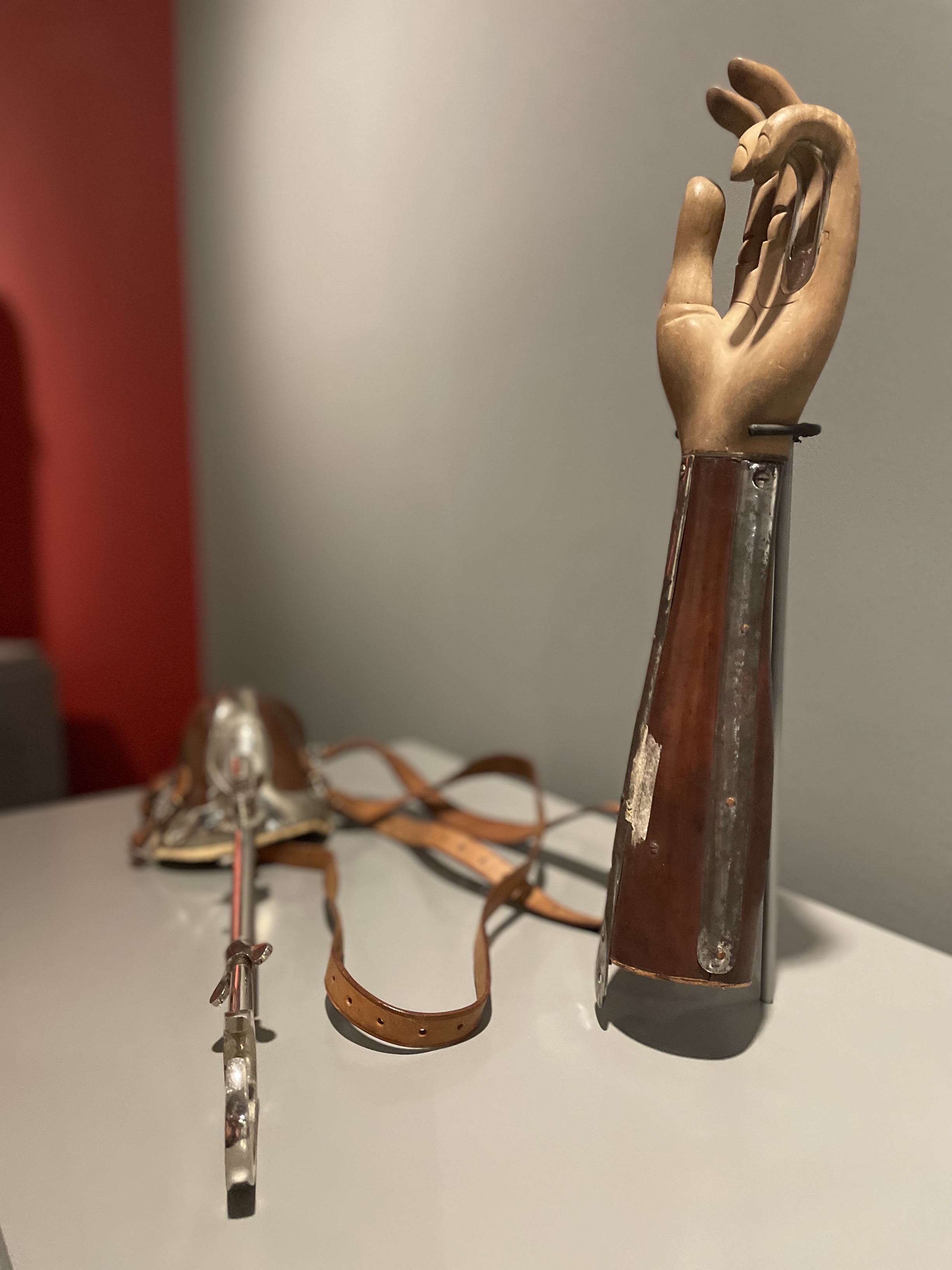 Modern photograph of a wooden hand and forearm prosthetic as well as its metal support structure and attached leather straps