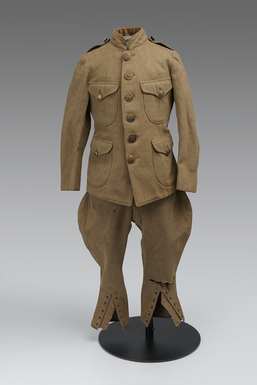 Photographie moderne d’une veste et d’un pantalon d’uniforme militaire marron de taille enfant.