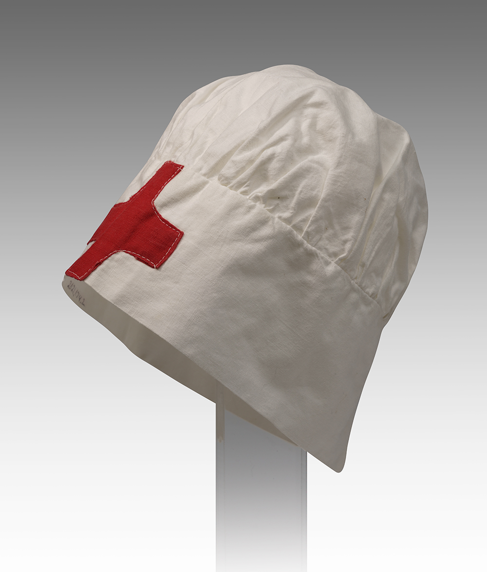 Photographie moderne d'une casquette blanche en forme de bonnet avec une croix rouge sur le bord