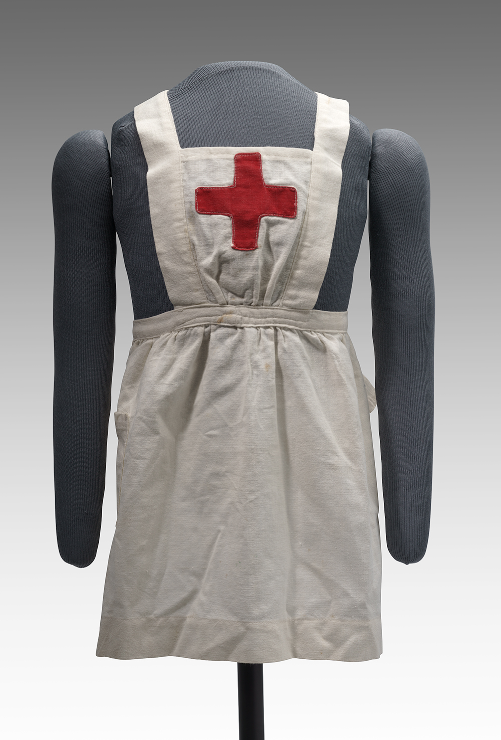 Photographie moderne d'un petit tablier à blouse blanche avec une croix rouge sur le devant