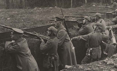 Black and white photograph of a group of soldiers in a trench looking over the far edge away from the viewer.