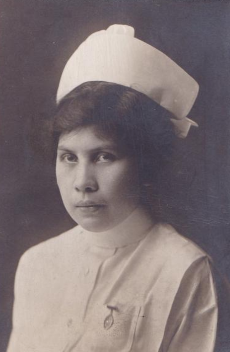 Black and white portrait photograph of a Native American woman in a white nurse uniform