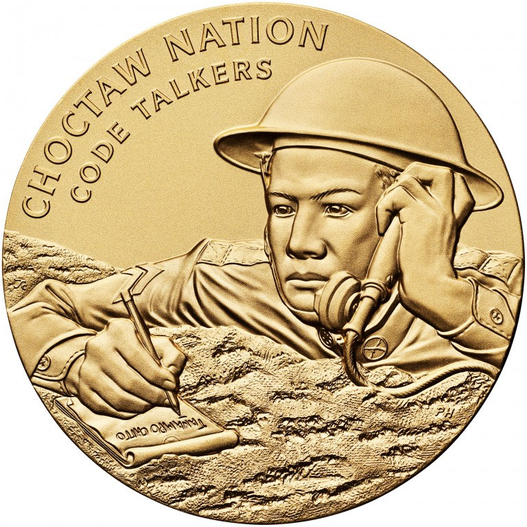 Photographie moderne d'une médaille de couleur bronze-or gravée d'une image d'un soldat de la Première Guerre mondiale prenant des notes et communiquant via une radio de campagne ou un téléphone. Texte : « Nation Choctaw / Code Talkers »