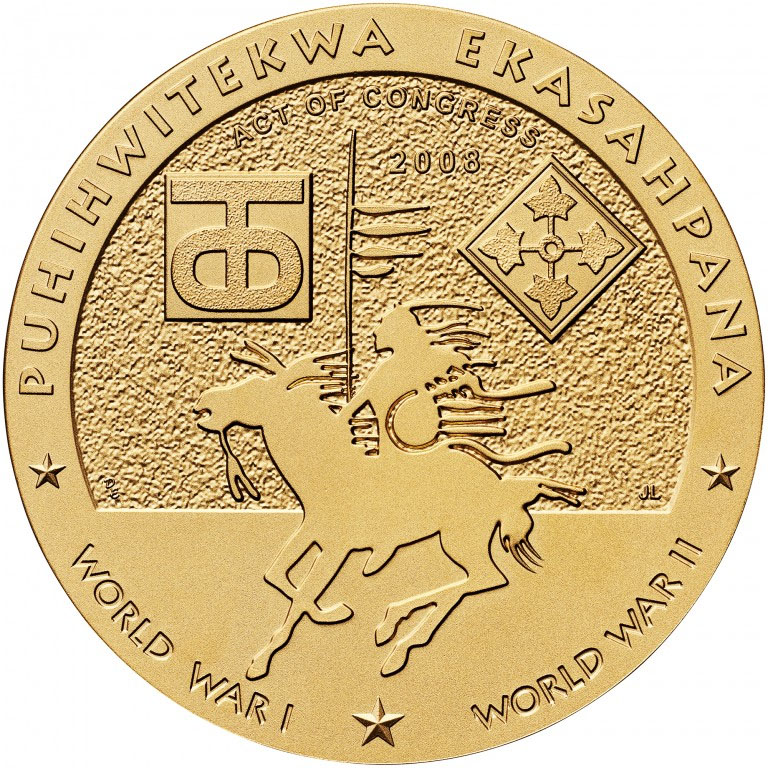 Photographie moderne du dos d'une médaille de couleur bronze doré gravée d'un guerrier amérindien monté sur un cheval ainsi que de plusieurs autres symboles nationaux Comanche. Texte : « Puhihwitekwa Ekasahpana »