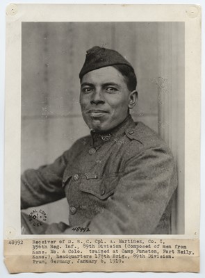 Portrait photograph of a soldier named Augustine Martinez. The text attached on the image explains that he was a Distinguished Service Cross recipient. The soldier is wearing his uniform with his overseas cap.