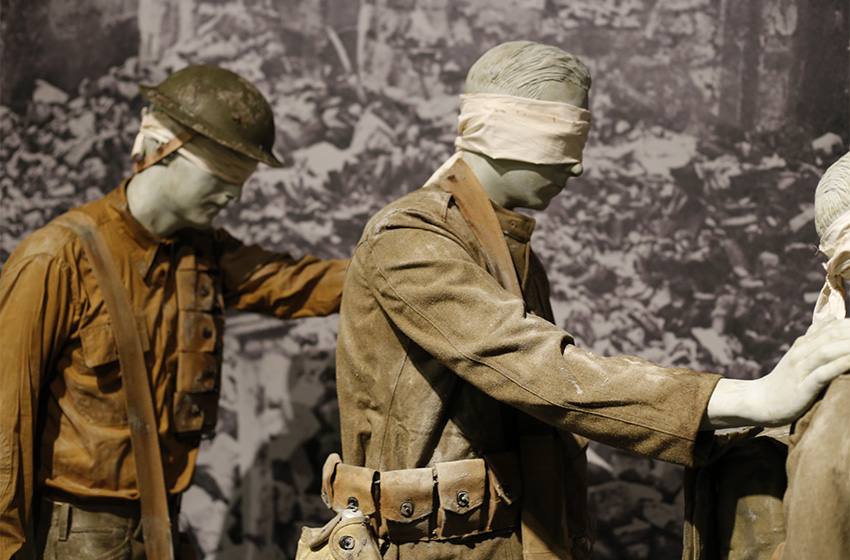 Modern photograph showing a closeup on the gassed soldier mannequins, dressed in dusty and dirty uniforms.