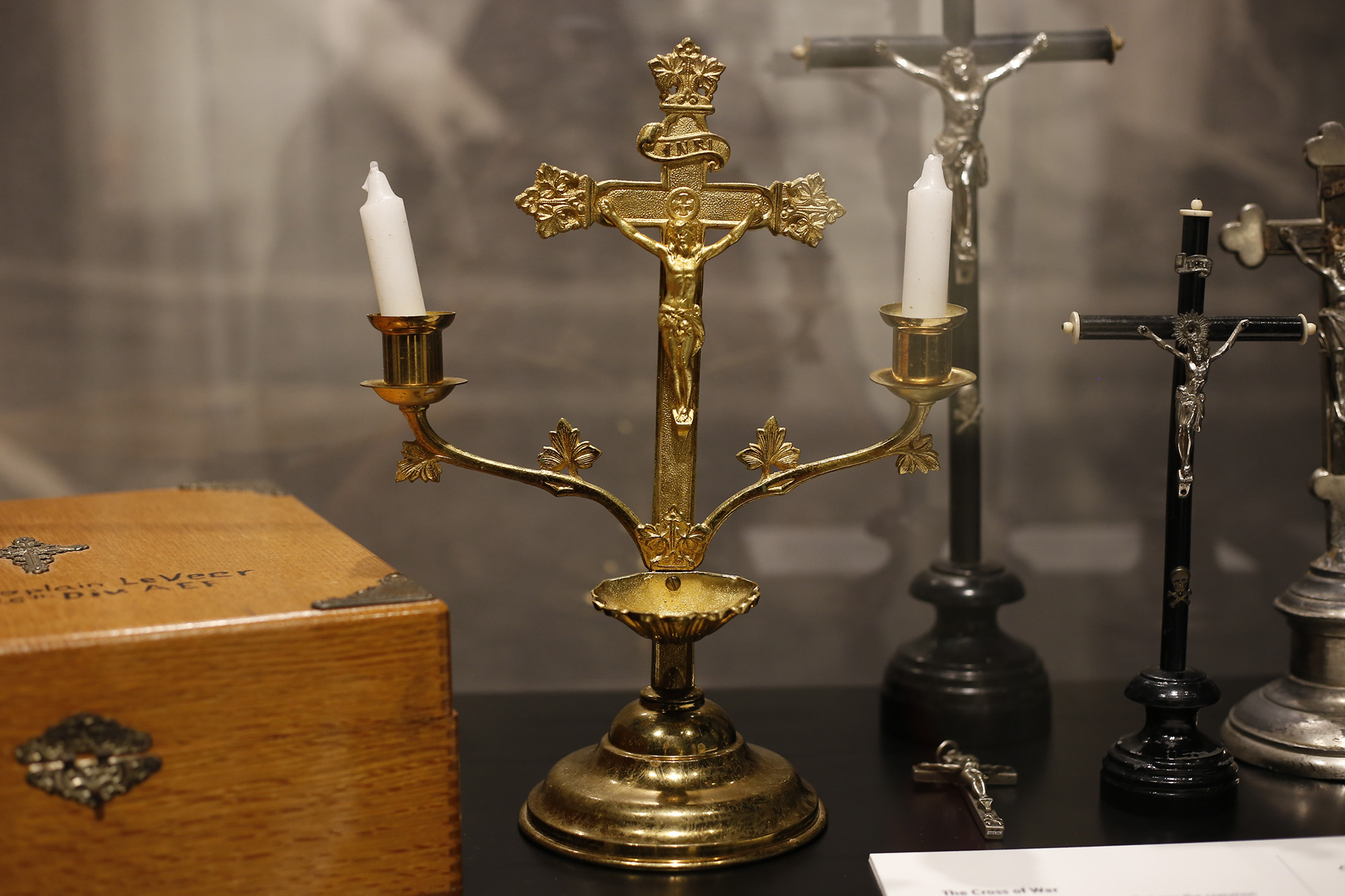 Photographie moderne d'un crucifix en or avec deux branches pour chandeliers.