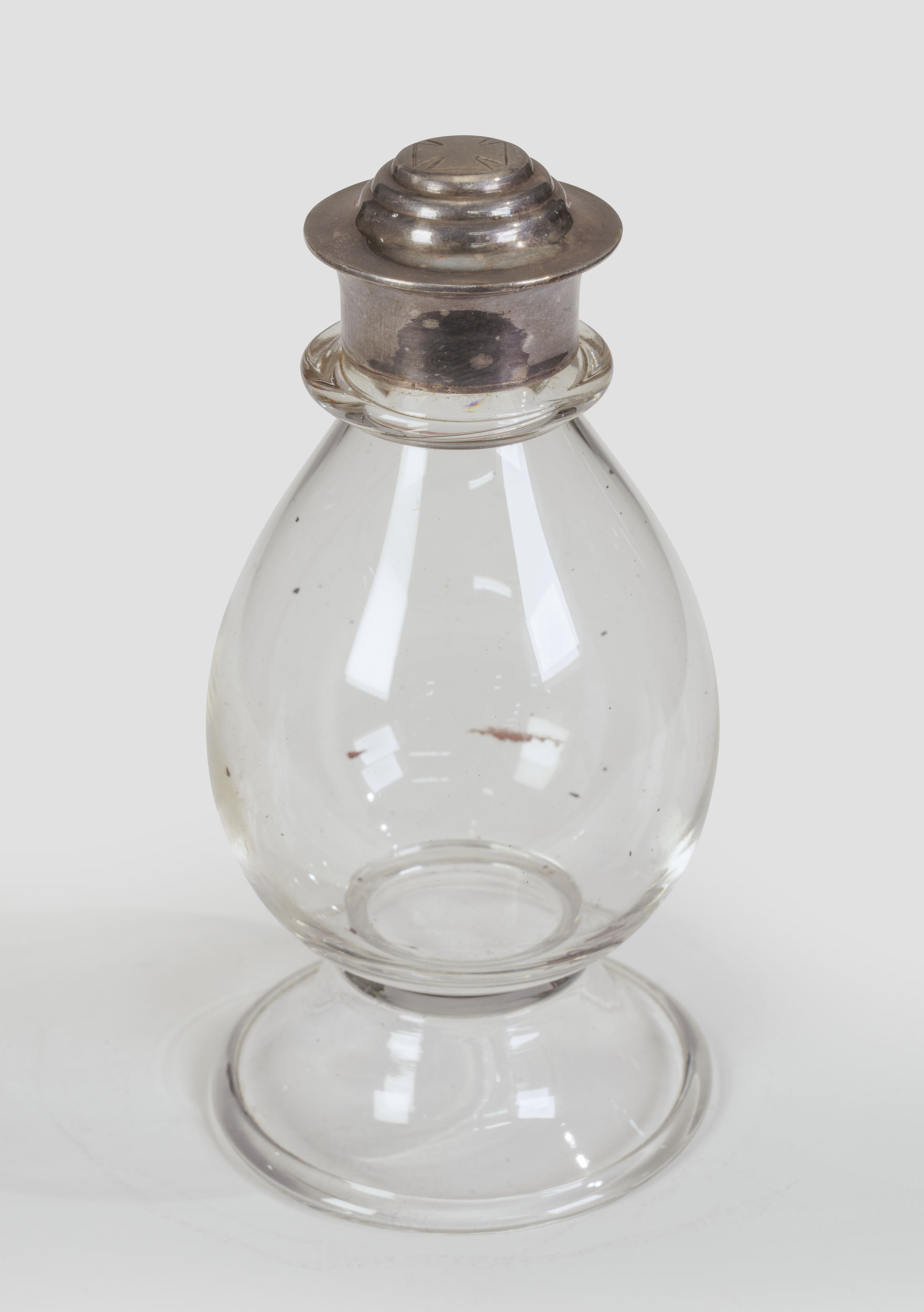 Photographie moderne d'un récipient en verre soufflé en forme de bulbe avec un bouchon en argent