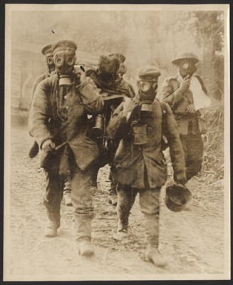 Black and white photograph of German prisoners of war carrying a wounded soldier on a stretcher while wearing German made gas masks.