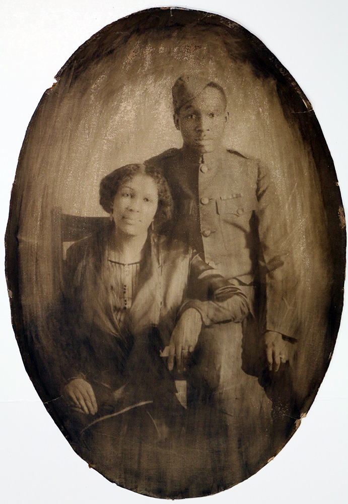 Oval photograph of an African American soldier and his wife. Some smoke damage around edges.