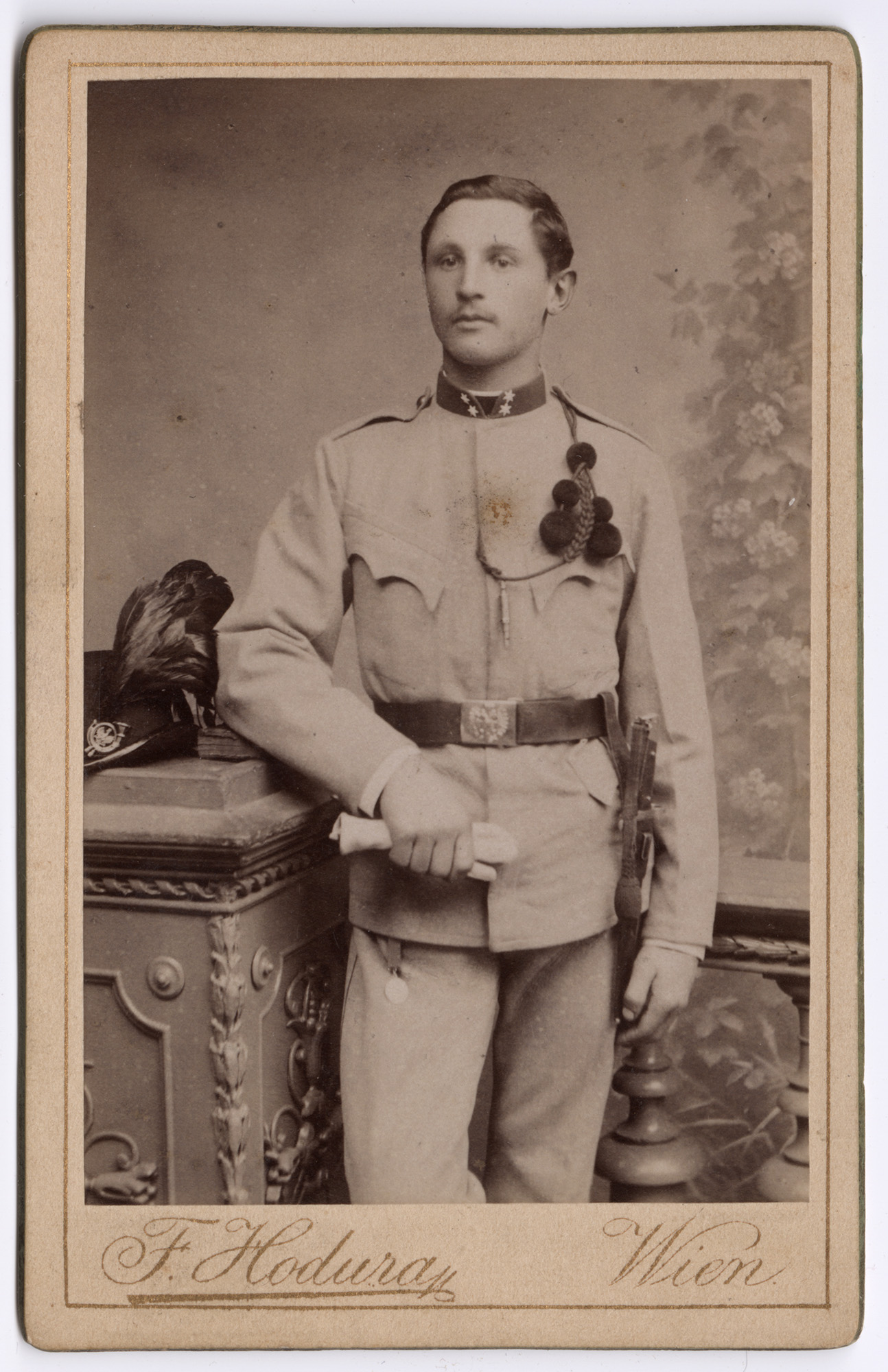 Black and white portrait photograph of a young white man in dress uniform wearing a lanyard with pom-poms and a whistle hanging from it