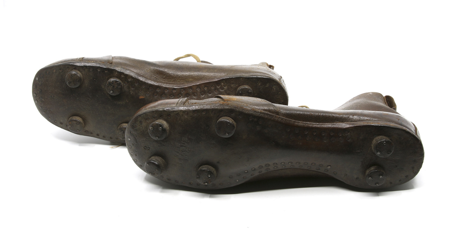 Leather boot-shaped footwear, each one laid on its side so viewer can see six thick cleats attached to the soles
