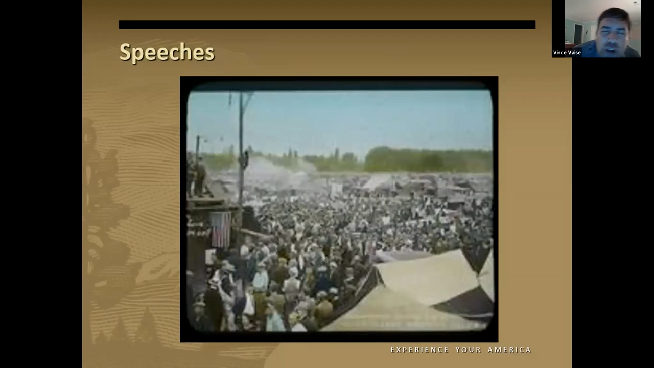Colorized photograph of a crowd gathered around a stage in the encampment