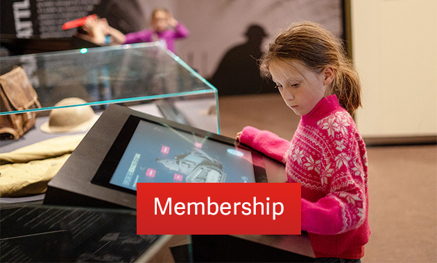 A young Museum guest in a pink sweater touches an interactive display about a WWI Renault tank. Text: 'Membership'