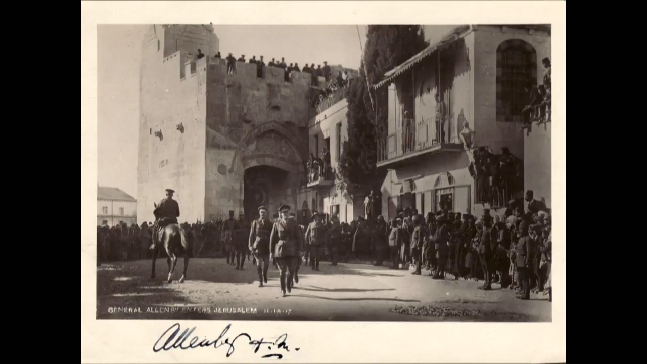Black and white photo of WWI British officers entering through a city gate on foot