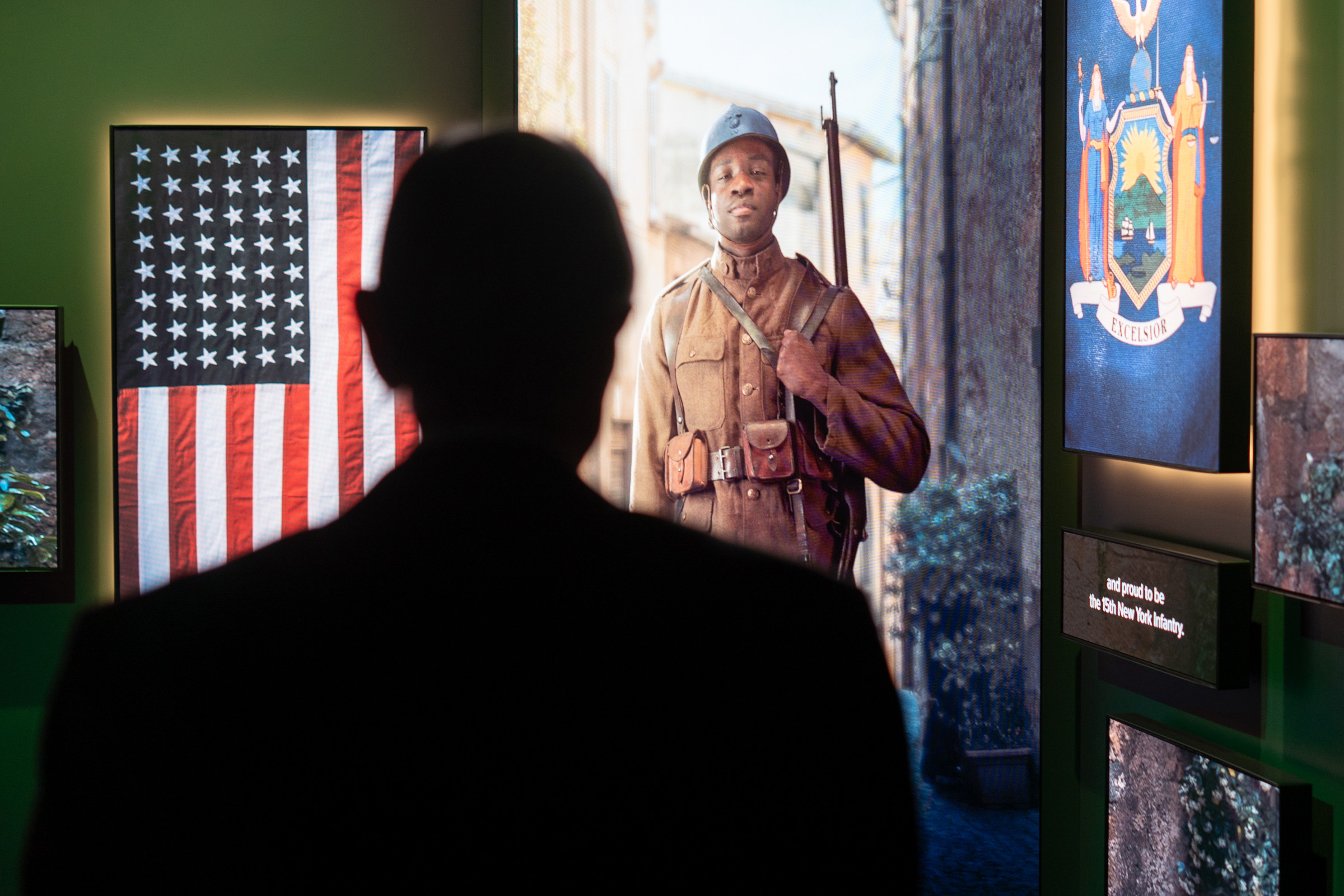 A museum guest watches a life-size video projection of a Black WWI soldier