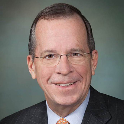 Older white man wearing glasses and a dark suit