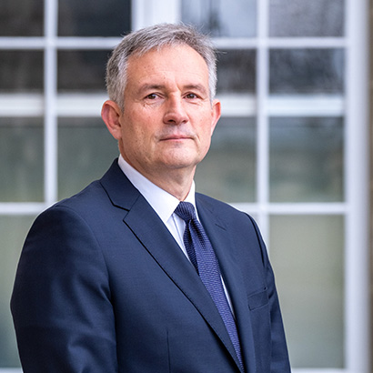 Older white man with short grey hair wearing a dark blue suit