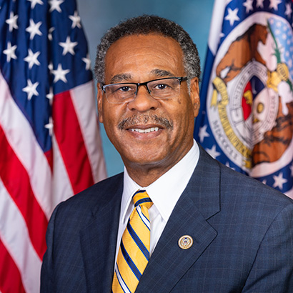Older Black man with greying hair and mustache wearing a dark blue suit